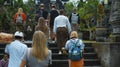 Photo of people walking on the rock stears in a sacred place with ancient stone buildings on the island of bali