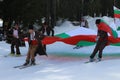 People dressed with traditional Bulgarian clothes skiing with the Bulgarian national flag. Royalty Free Stock Photo