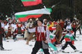 People dressed with traditional Bulgarian clothes skiing with the Bulgarian national flag. Royalty Free Stock Photo