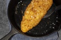 Pan fried breaded haddock fish in a cast iron frying pan.