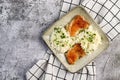 Pan fried chicken thighs with rice and herbs on a white square plate on a dark background Royalty Free Stock Photo