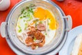 A pan fried egg with toppings on the red table.