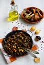 Pan with fried forest mushrooms on a checkered napkin, onions, sunflower oil and peppercorns on a light background