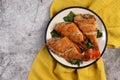 Pan Fried Rose fish with herbs on a round plate on a dark background.