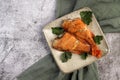 Pan Fried Rose fish with herbs on a square plate on a dark background.