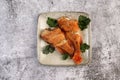 Pan Fried Rose fish with herbs on a square plate on a dark background