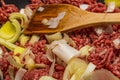 Pan of lean minced beef and leeks with a wooden utensil