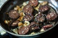 Pan with morcilla sausage slices frying with onions