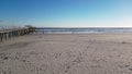 Pan from wooden pier to deserted beach on a sunny winter day