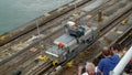 A cruise ship with the passengers on the bow watching the ship being drug by a mule train locomotives at the Panama Canal