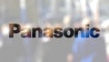 Panasonic Corporation logo on a glass against blurred crowd on the steet. Editorial 3D rendering