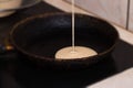 Pancake batter baking mix being poured from a bowl onto a hot electric griddle cooking delicious breakfast meal for a family