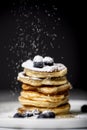 Pancake pile with blueberry sifting powdered sugar on the top of it.