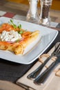 Pancake with salmon and sourcream and dille on a white plate.