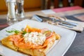 Pancake with salmon and sourcream and dille on a white plate.