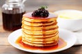 pancake stack with a small jug of syrup tipped over next to it