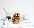 Pancake tower with fresh figs and honey on a rustic plate. White background Royalty Free Stock Photo