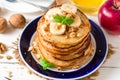 Pancakes with banana, honey, walnuts and mint on plate.