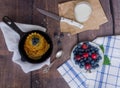 Pancakes with berries blueberries and cherries.pancakes in a frying pan on a wooden table with a plate of fresh juicy berries on a