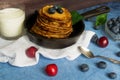 Pancakes with berries blueberries and cherries.pancakes in a frying pan on a blue table with a plate of fresh juicy berries on a Royalty Free Stock Photo