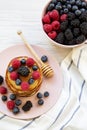 Pancakes with berries and honey on a pink plate, bowl of berries, high angle. Royalty Free Stock Photo