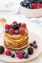 Pancakes with berries and honey on a pink plate, side view. Royalty Free Stock Photo