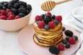 Pancakes with berries and honey on a pink plate, side view. Royalty Free Stock Photo
