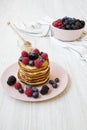 Pancakes with berries and honey on a pink plate, side view. Royalty Free Stock Photo