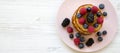 Pancakes with berries and honey on a pink plate, top view. Overhead, flat lay, from above. Copy space Royalty Free Stock Photo