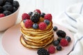 Pancakes with berries and honey on a round pink plate, side view. Royalty Free Stock Photo