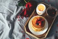 Pancakes with berries, roses flowers, cup of tea and candle in candlestick. Valentine`s day breakfast concept. Top view with copy Royalty Free Stock Photo