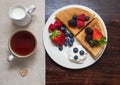 Pancakes with berries and sour cream on a dark background. Healthy and delicious breakfast. Sweet pancakes in a white plate Royalty Free Stock Photo