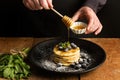 Pancakes with blueberries on a black plate and a man dipping honey Royalty Free Stock Photo
