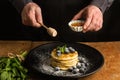 Pancakes with blueberries on a black plate and a man with a honey dipper Royalty Free Stock Photo