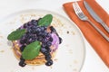 Pancakes with blueberries, cream and jam on white plate in a restaurant. Close-up, selective focus. Tasty breakfast, morning