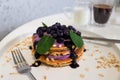 Pancakes with blueberries, cream and jam on white plate in a restaurant. Close-up, selective focus. Tasty breakfast, morning