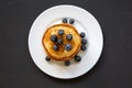 Pancakes with blueberries and honey on white plate on dark wooden background, top view. Flat lay Royalty Free Stock Photo