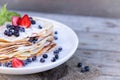 Pancakes with blueberries and mint leaf on top. A bunch of big homemade pancakes with forest fruits. A pile of flat thin