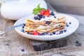 Pancakes with blueberries and mint leaf on top. A bunch of big homemade pancakes with forest fruits. A pile of flat thin