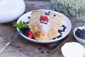 Pancakes with blueberries and mint leaf on top. A bunch of big homemade pancakes with forest fruits. A pile of flat thin