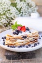 Pancakes with blueberries and mint leaf on top. A bunch of big homemade pancakes with forest fruits. A pile of flat thin