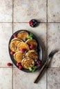 Pancakes in brown ceramic plate with berries, mint leaves and a fork, top view Royalty Free Stock Photo