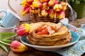 Pancakes with caviar and butter, a bouquet of fresh tulips and a wooden background. Traditional Russian food for carnival. Top