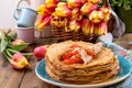 Pancakes with caviar and butter, a bouquet of fresh tulips and a wooden background. Traditional Russian food for carnival. Top