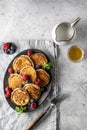 Pancakes in ceramic plate with berries, mint leaves, gravy boats and fork on napkin, top view Royalty Free Stock Photo