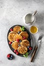 Pancakes in ceramic plate with berries, mint leaves, gravy boats and fork, top view Royalty Free Stock Photo