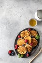Pancakes in ceramic plate with berries, mint leaves, gravy boats and honeyspoon, top view Royalty Free Stock Photo