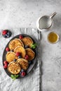 Pancakes in ceramic plate with berries, mint leaves, gravy boats on linen napkin, top view Royalty Free Stock Photo