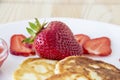 Pancakes with cheese and strawberries and sauce on a white dish against wood background. Delicious cheese pancake and strawberries Royalty Free Stock Photo