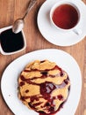Pancakes with cherry jam on a white table. a cup of tea. Royalty Free Stock Photo
